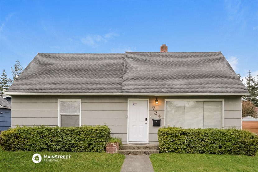 a small gray house with a white door and a lawn