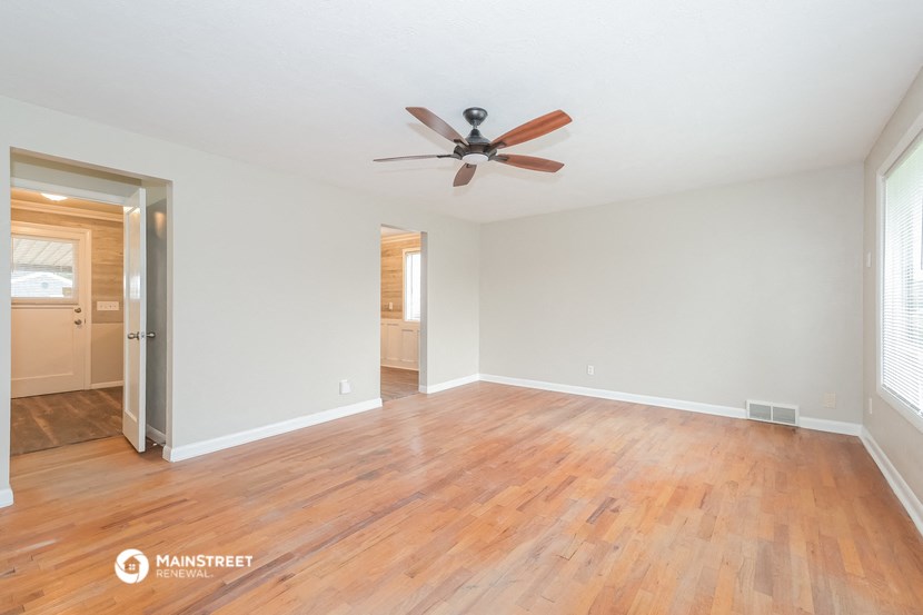 the living room with wood floors and a ceiling fan
