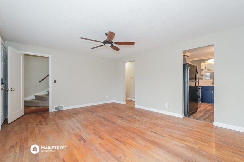 an empty living room with wood floors and a ceiling fan