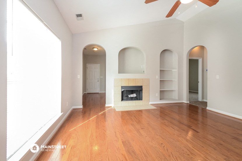 an empty living room with a fireplace and wooden floors
