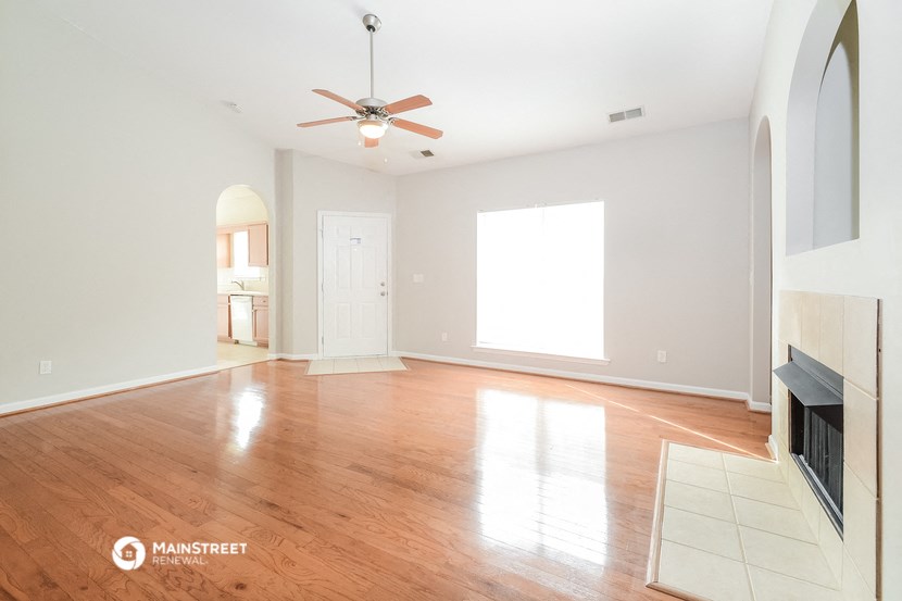 an empty living room with wood floors and a ceiling fan