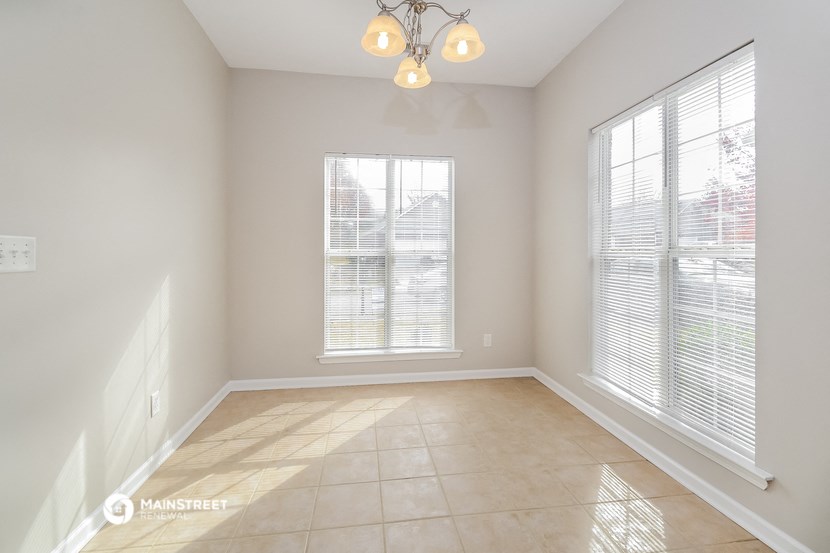 an empty living room with two windows and a tiled floor