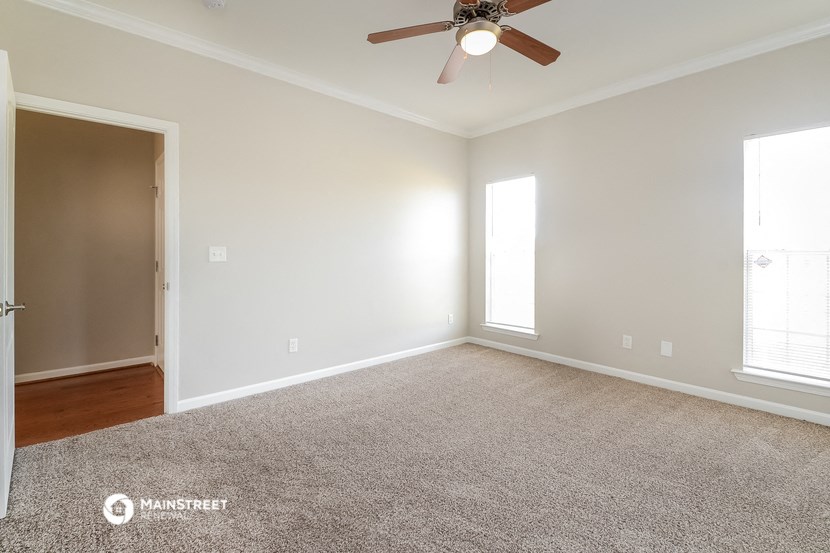 an empty living room with a ceiling fan and carpet