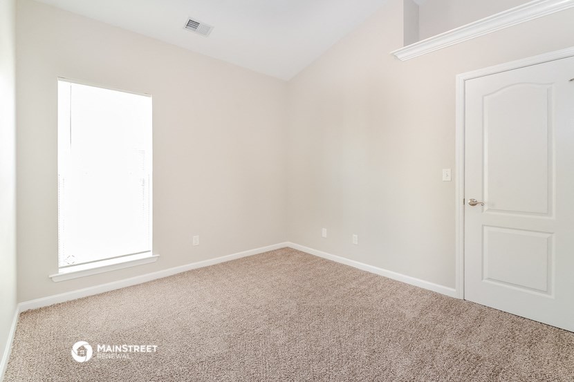 a bedroom with a carpeted floor and a white door