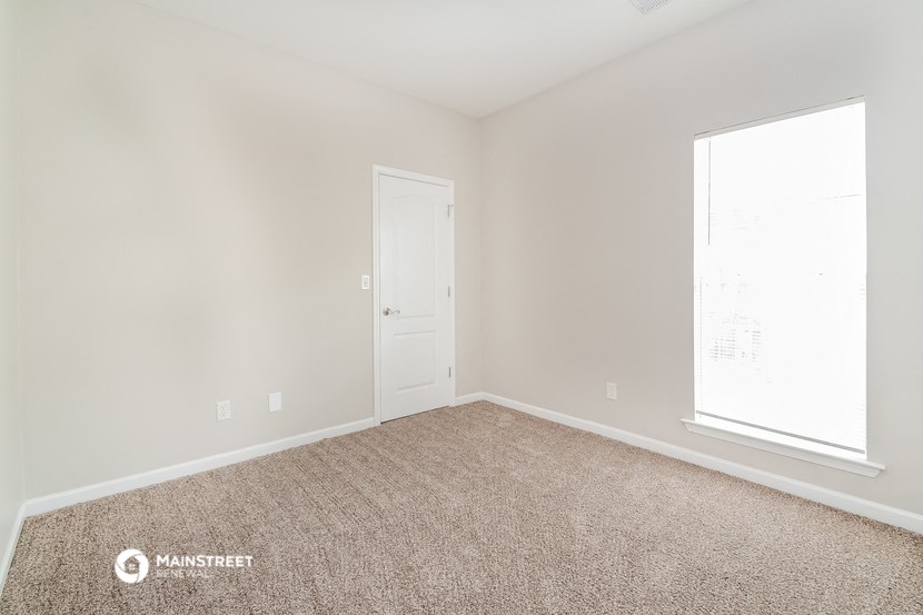 a bedroom with a carpeted floor and a white door