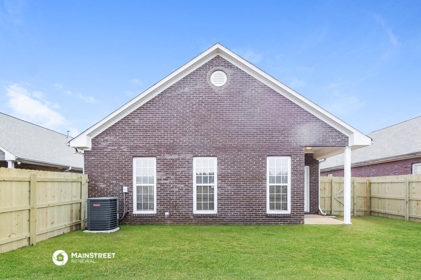 the backyard of a brick house with a wooden fence and grass