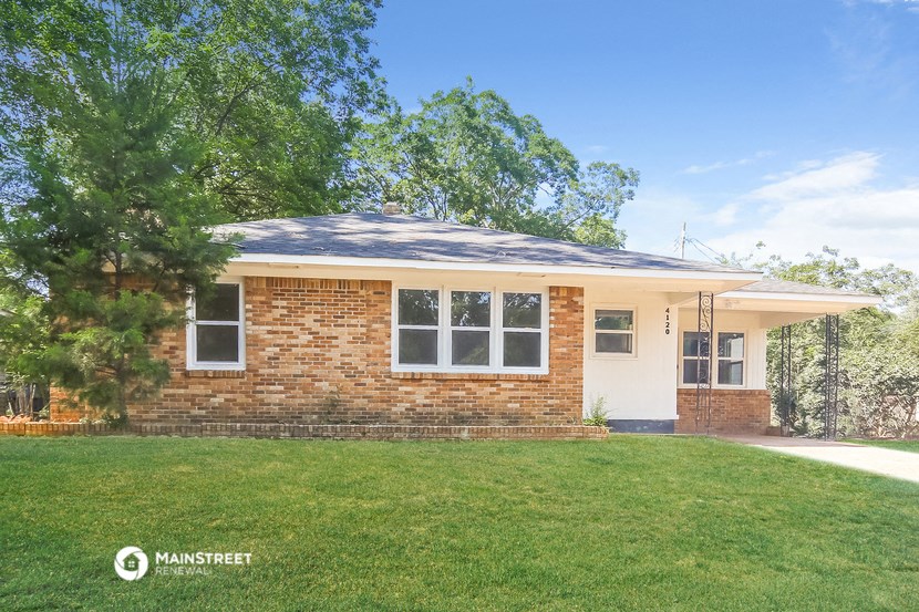a small brick house with a lawn and a tree