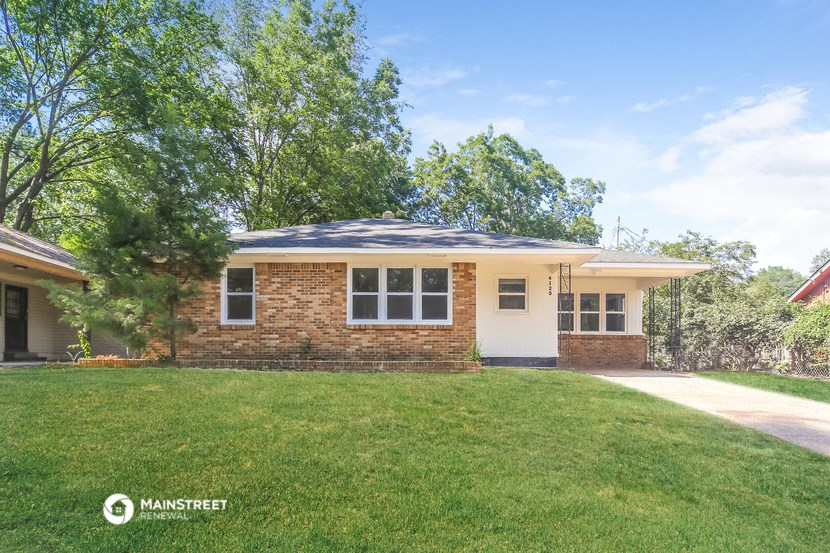 a small brick house with a lawn and a tree