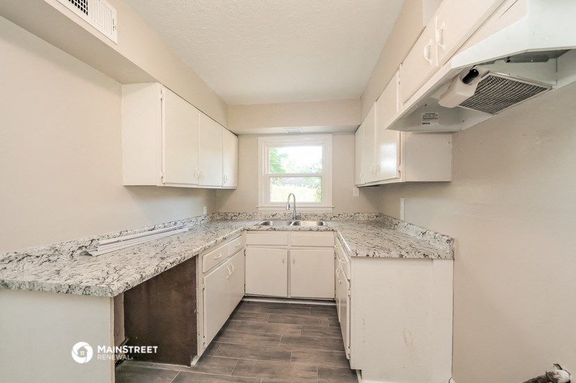 an empty kitchen with white cabinets and granite counter tops