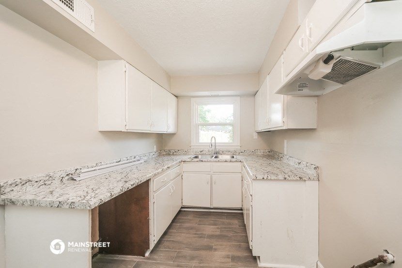 an empty kitchen with white cabinets and granite counter tops