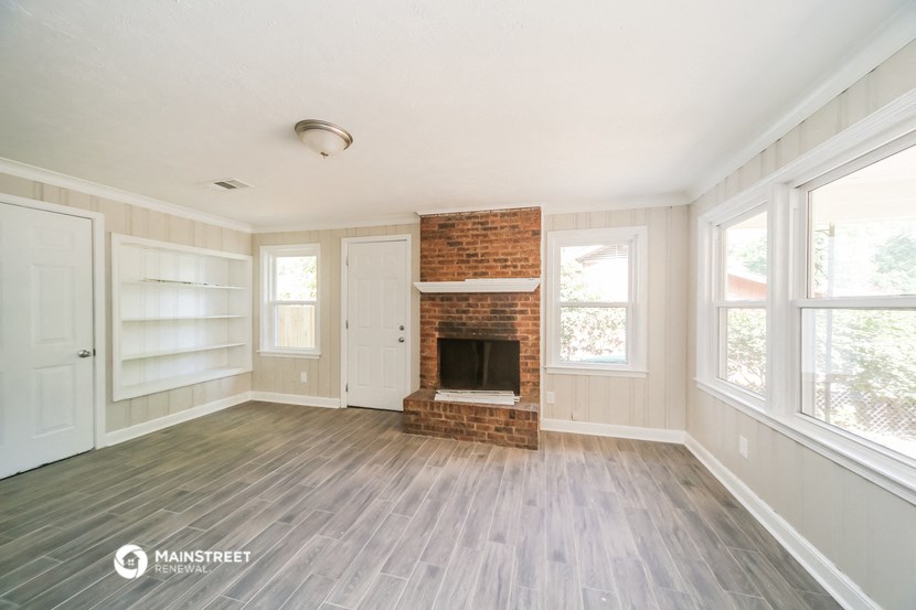 a living room with a brick fireplace and a wooden floor