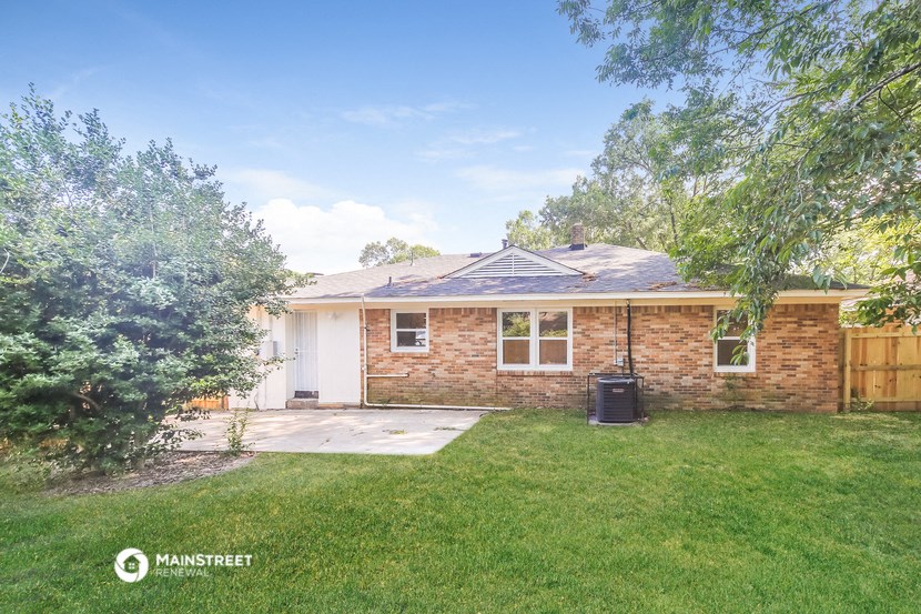 a small brick house with a yard and a tree