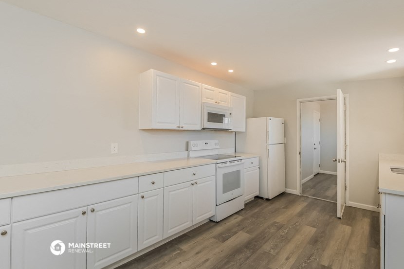 a kitchen with white cabinets and white appliances and a refrigerator