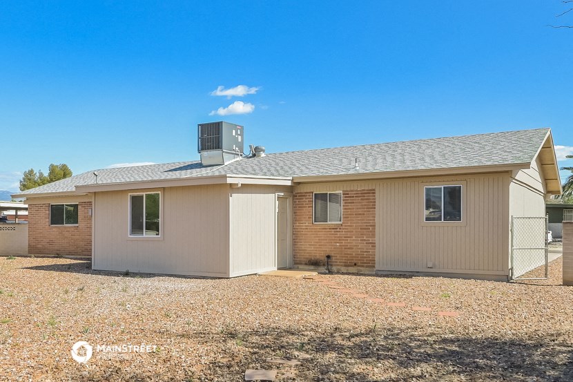 a small brick house with a roof and a gravel yard