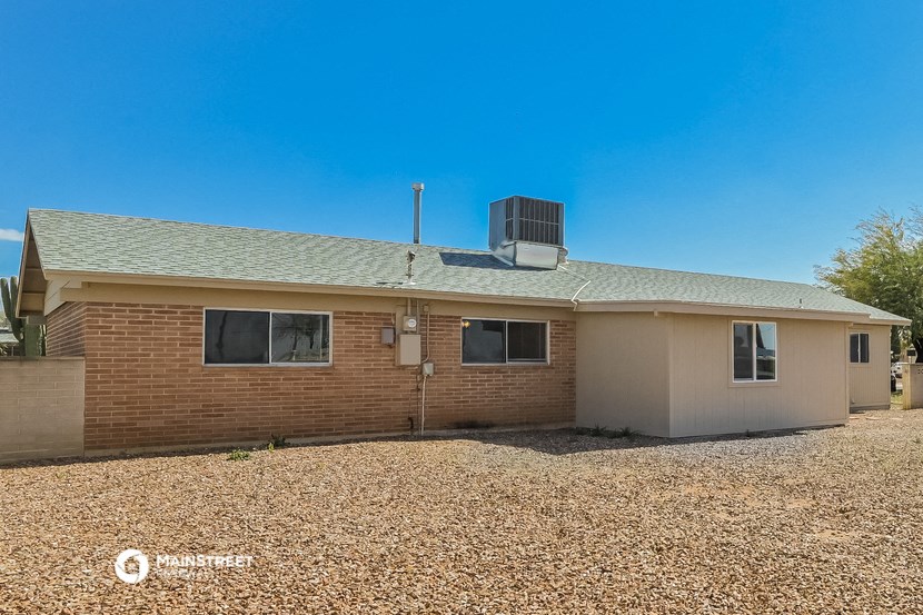 a small brick house with a gravel yard and a blue sky