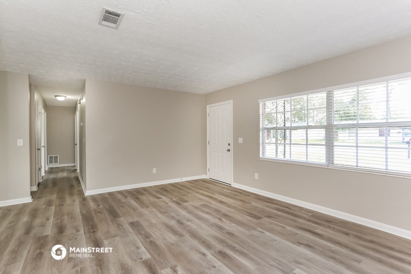 the spacious living room with a large window and wood flooring