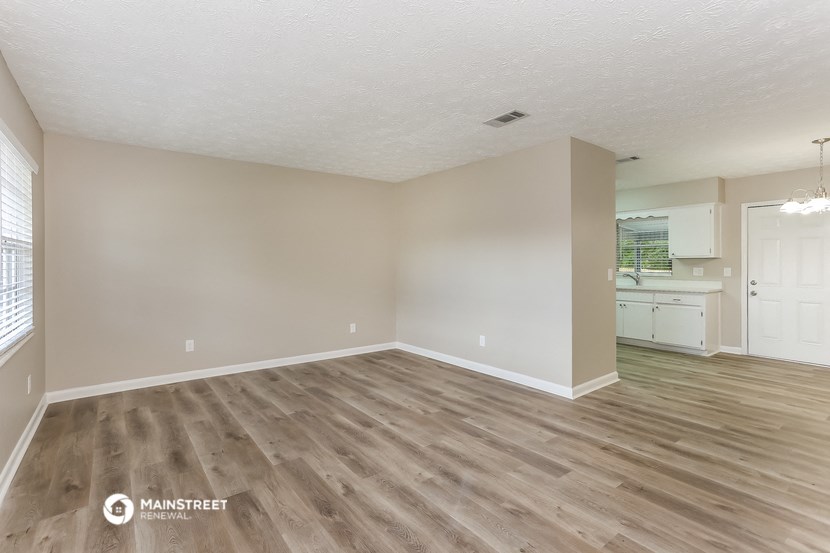 the living room and kitchen of an apartment with wood flooring