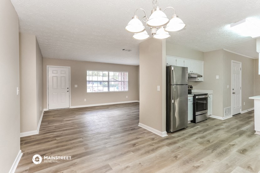 an empty kitchen and living room with a stainless steel refrigerator