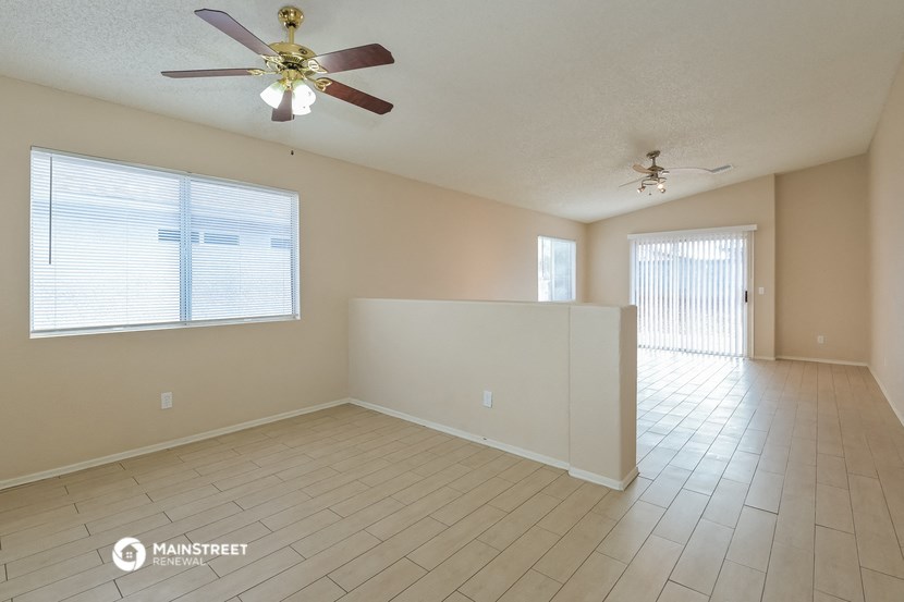 the living room and dining room of an empty home with a ceiling fan