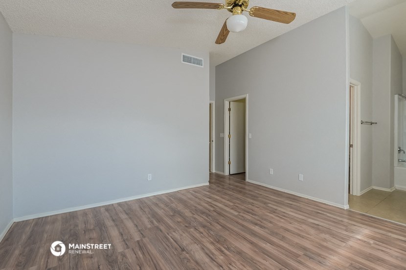 the spacious living room with wood flooring and ceiling fan