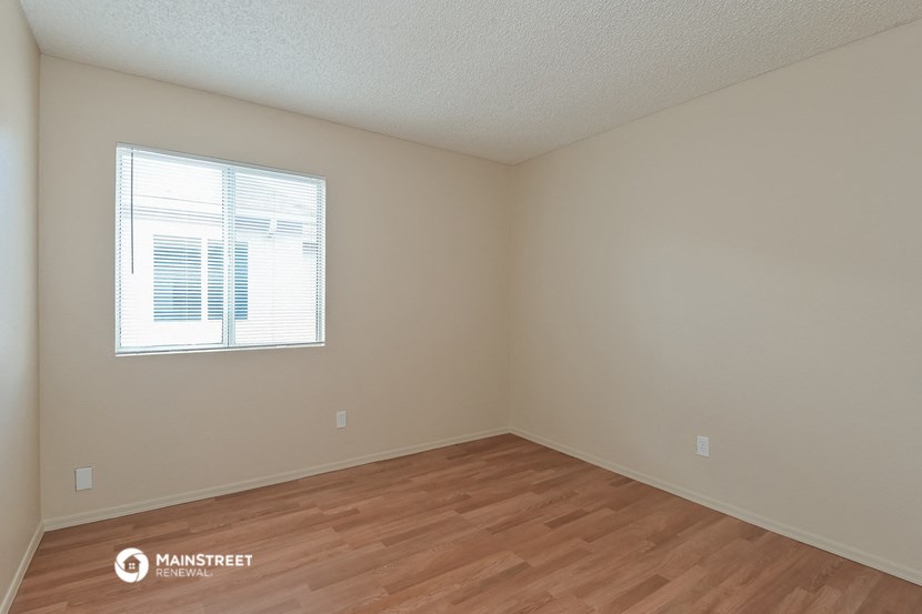 the spacious living room with wood flooring and a window