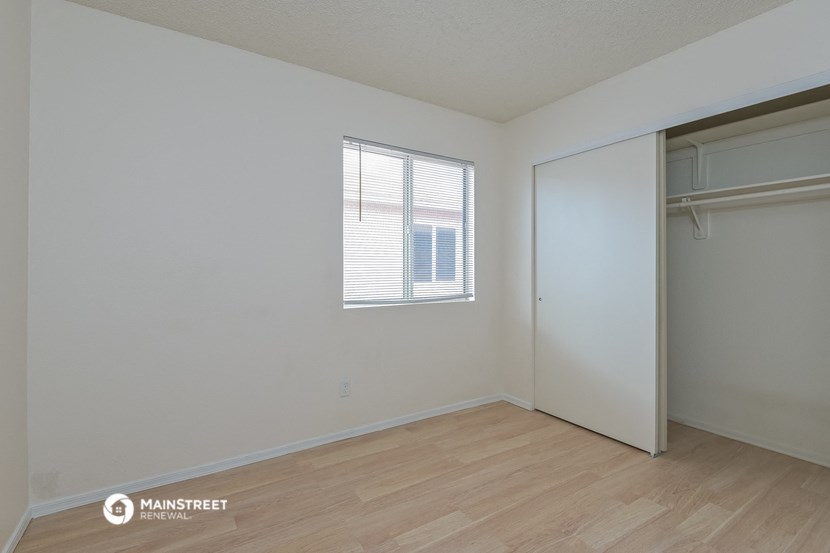 a bedroom with a closet and a window and a wooden floor