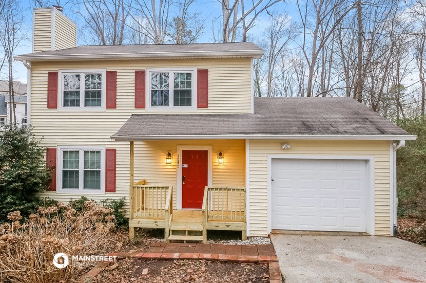 a yellow house with a red door and a white garage