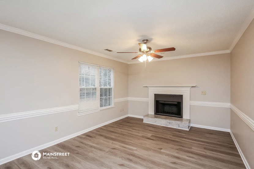 the spacious living room with fireplace and ceiling fan