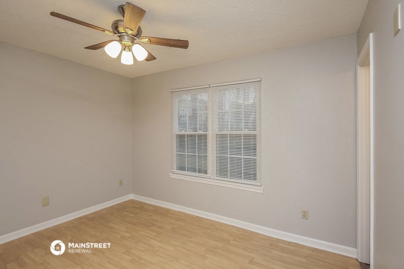 the spacious living room with a large window and a ceiling fan