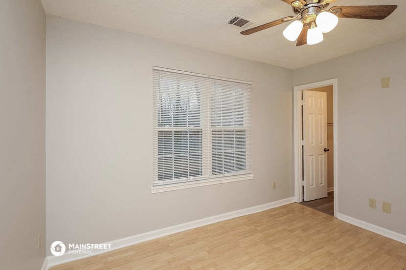 the spacious living room with a large window and a ceiling fan