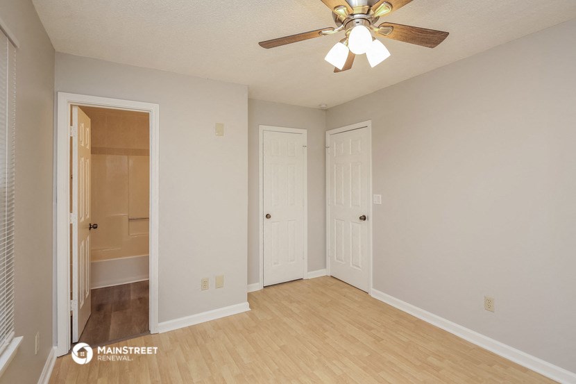 an empty living room with a ceiling fan and a closet