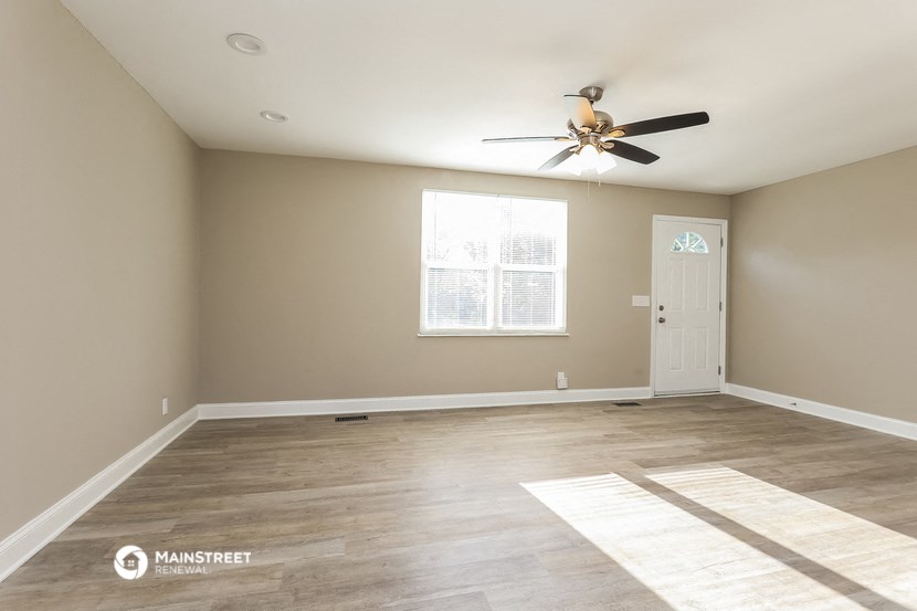 the spacious living room with ceiling fan and wood flooring