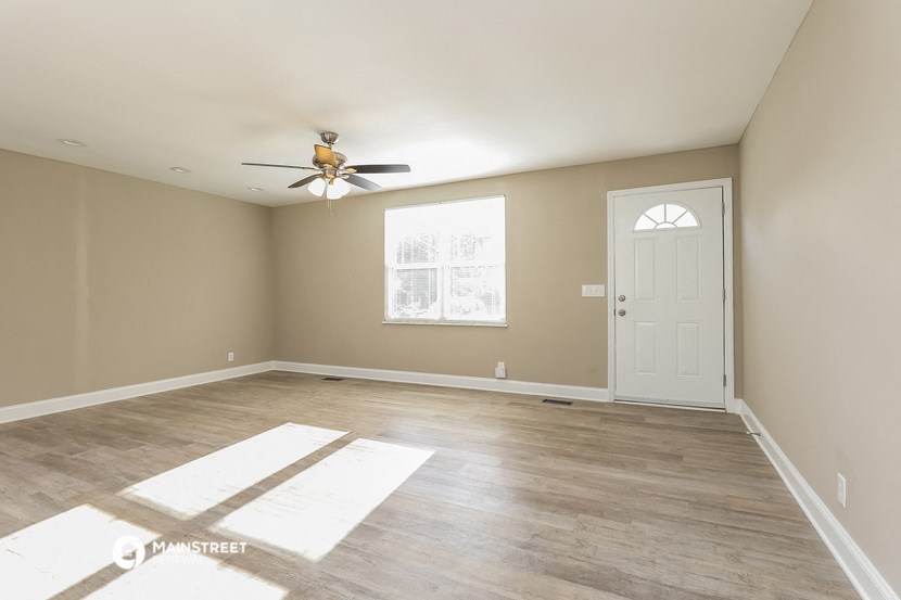 the living room of an empty house with a ceiling fan