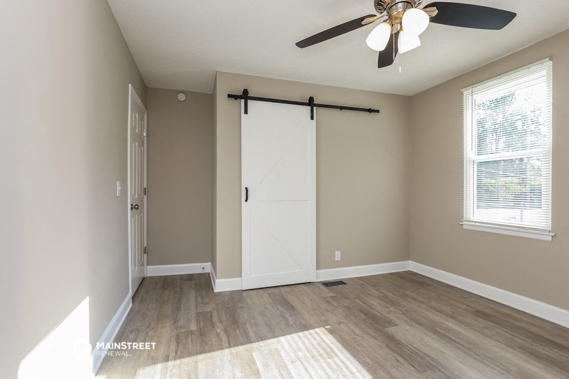 an empty room with a ceiling fan and a white sliding door