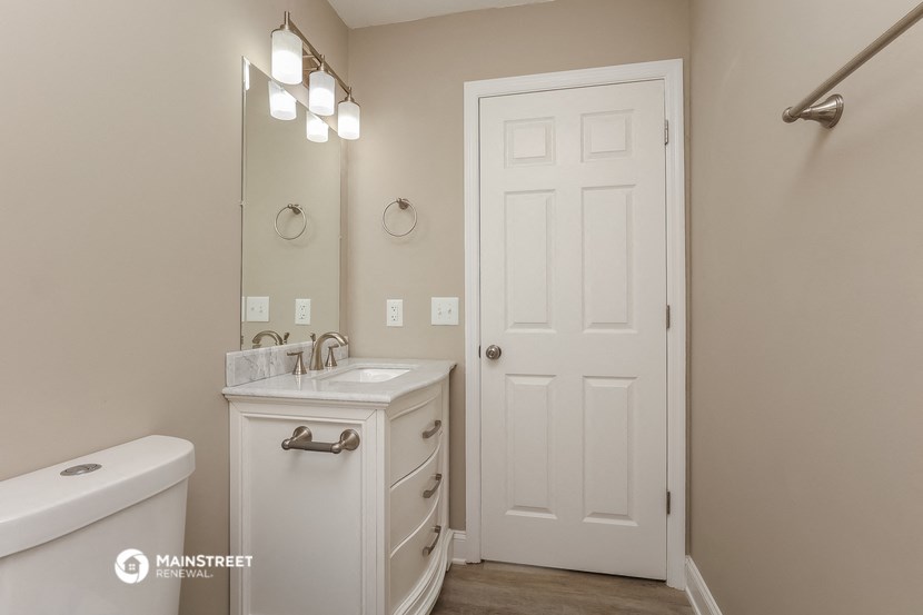 a bathroom with a white door and a sink and a mirror