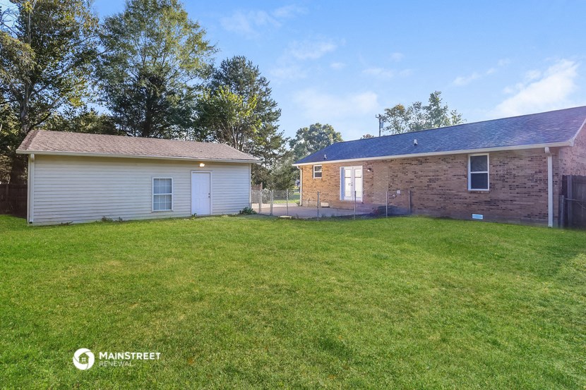 a backyard with a brick house and a grass yard