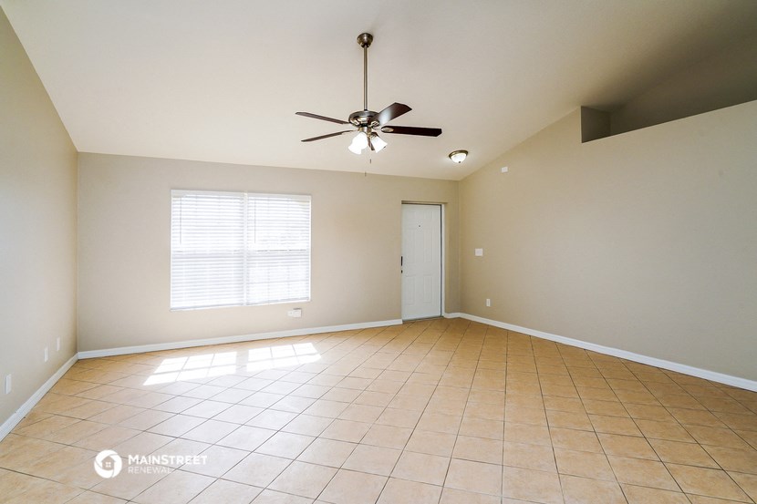 an empty living room with tiled floors and a ceiling fan