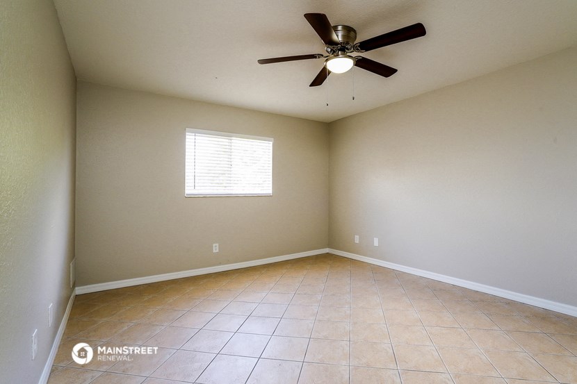 an empty living room with a ceiling fan and tiled floors