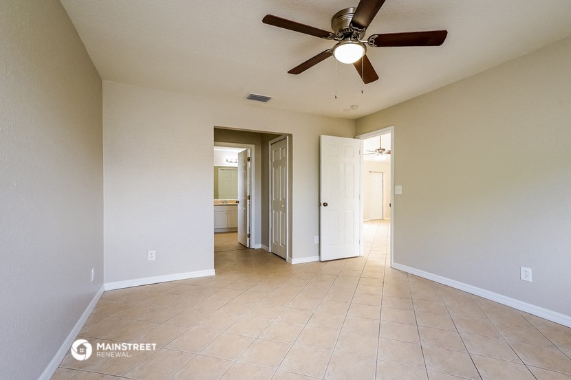 the spacious living room with ceiling fan and tiled floors