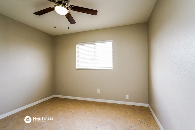 an empty room with a ceiling fan and a window