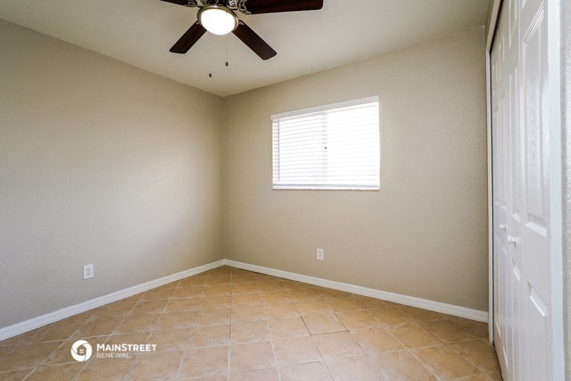 an empty room with a ceiling fan and a window