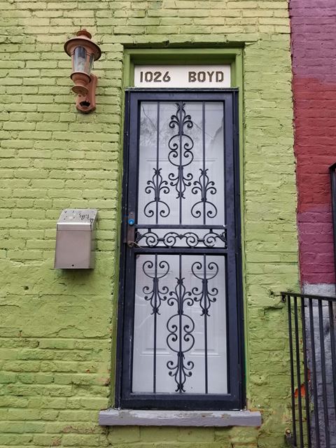 the front door of a brick building with a black wrought iron door