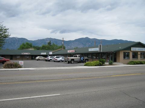 a city street with a store and a parking lot with mountains in the background