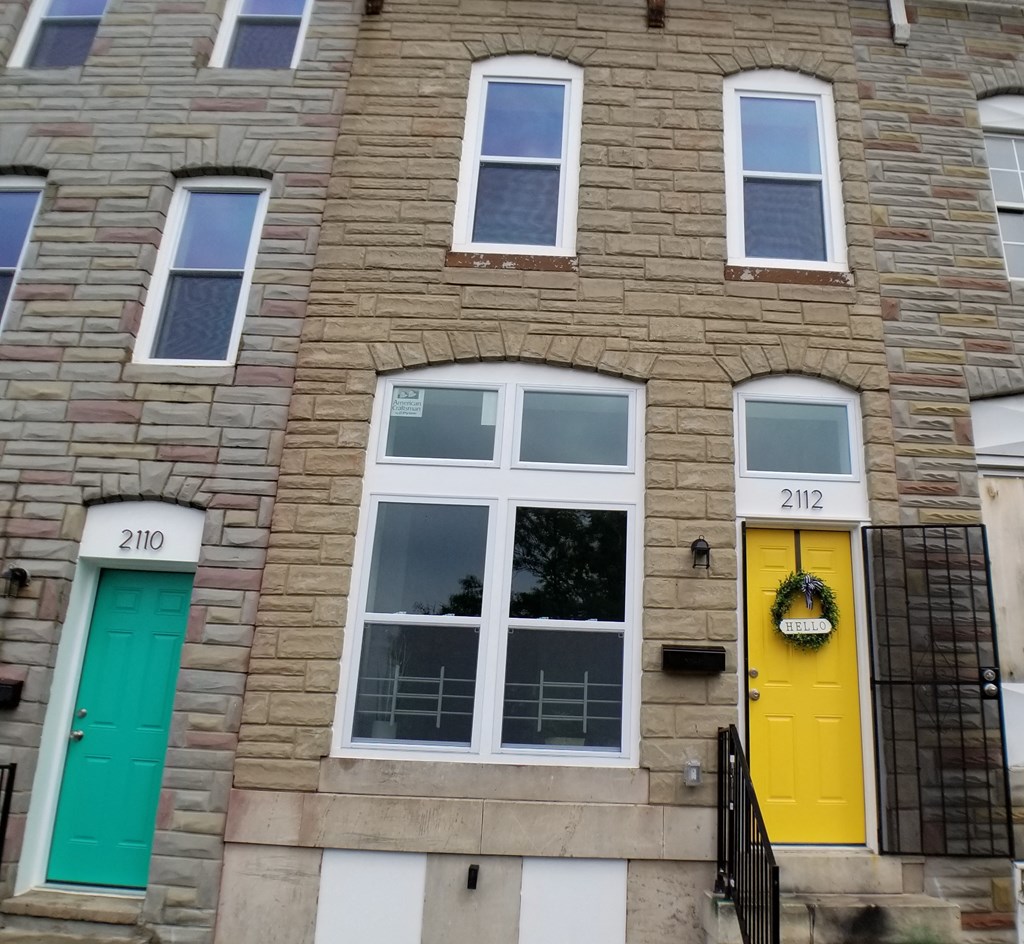the front of a brick house with yellow and green doors