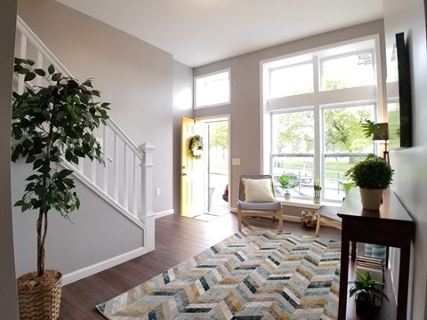 a living room with a rug in front of a staircase and a large window