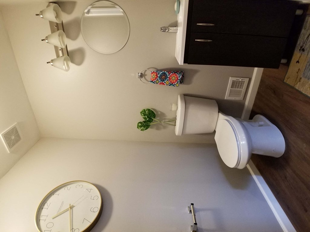 a bathroom with a clock and a toilet paper dispenser
