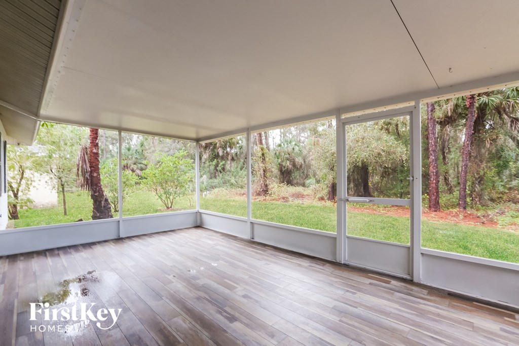 a room with wood floors and large windows overlooking the woods