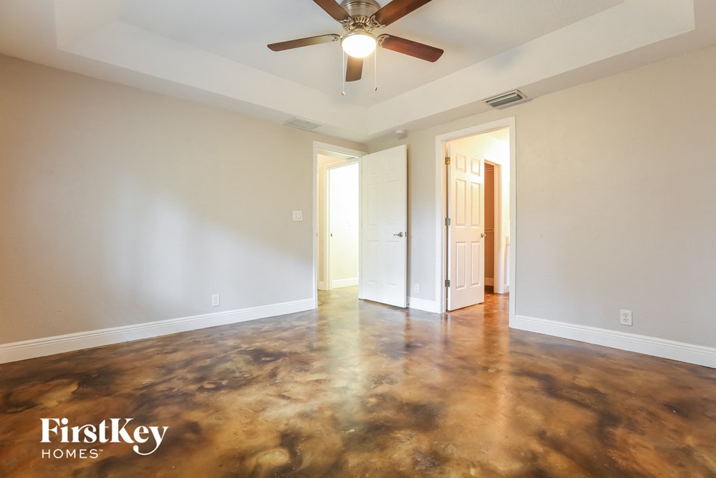 an empty living room with white walls and a ceiling fan