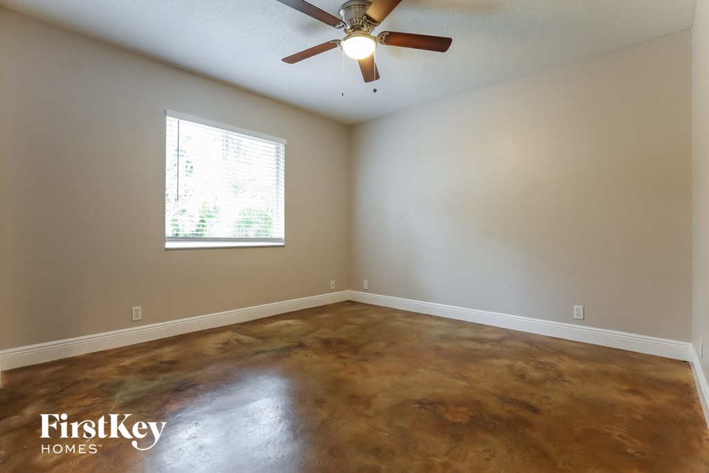 a empty living room with a ceiling fan and a window