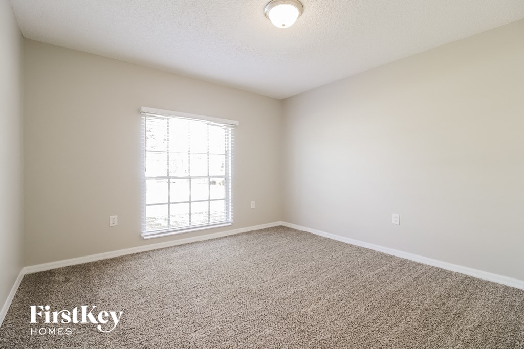 a spacious living room with carpet and a window